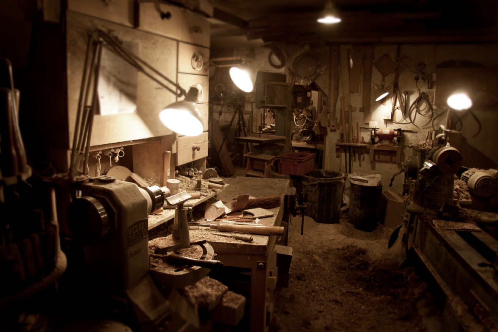 Atelier de menuisier éclairé par des lampes, avec établi, tour à bois et outils